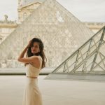 A woman in a dress standing in front of a pyramid