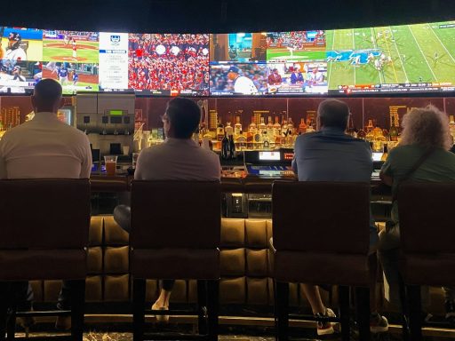 a group of people sitting at a bar watching tv
