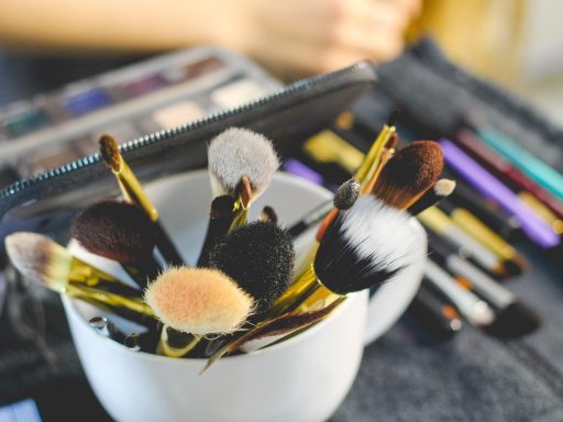 Zomerse make-up producten zoals lipgloss, mascara en blush neergelegd op een lichte ondergrond