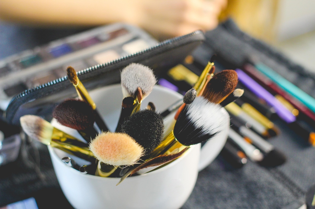 Zomerse make-up producten zoals lipgloss, mascara en blush neergelegd op een lichte ondergrond