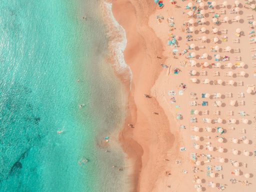 an aerial view of a beach with umbrellas and chairs