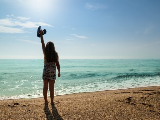 Vrouw op het strand met haar in de zon, zichtbaar droog en blootgesteld aan UV-straling