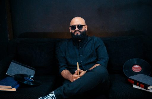 Man with beard and sunglasses sitting on sofa.