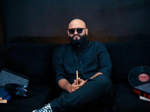 Man with beard and sunglasses sitting on sofa.