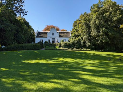 a white house surrounded by trees on a sunny day