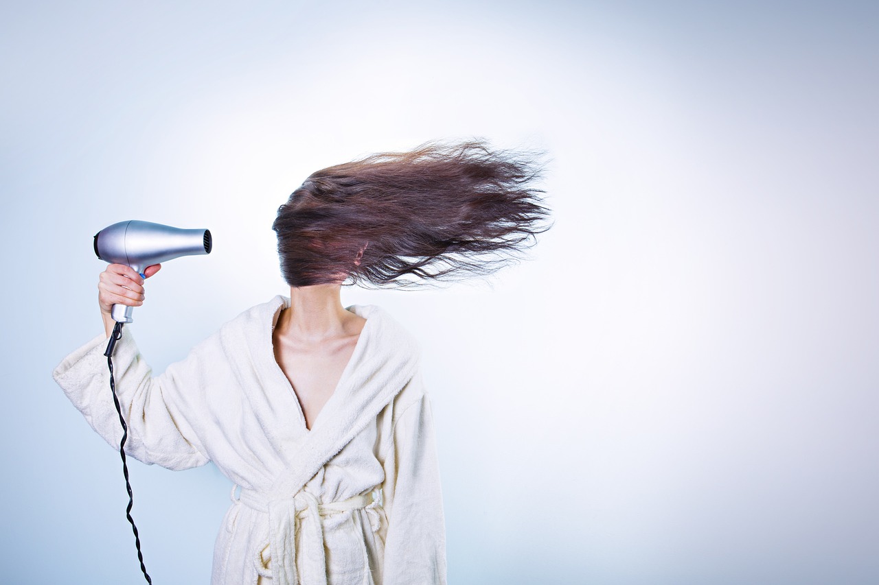 Vrouw die haar droge haar borstelt in een warme binnenruimte