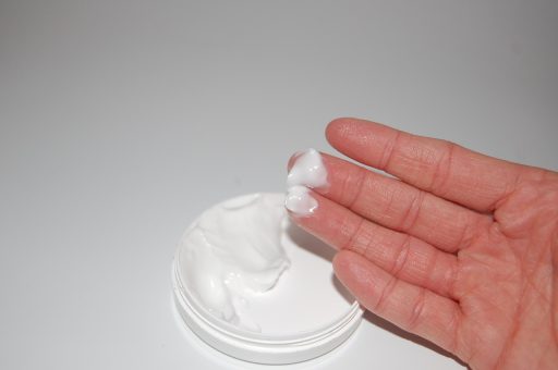 Vrouw die handcrème aanbrengt op droge, roodgekleurde handen
