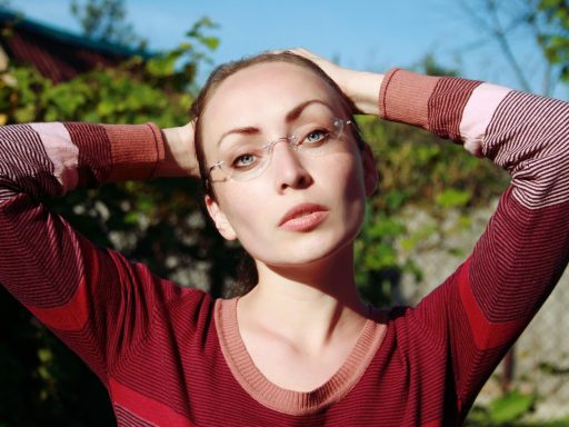 Vrouw met bril die oogmake-up aanbrengt voor een spiegel