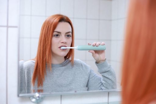 Vrouw die zorgvuldig haar tanden poetst in de badkamer als onderdeel van haar dagelijkse beauty routine