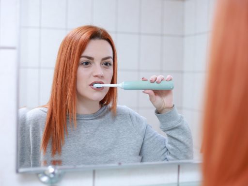 Vrouw die zorgvuldig haar tanden poetst in de badkamer als onderdeel van haar dagelijkse beauty routine