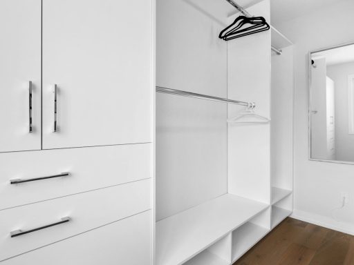 a walk in closet with white cabinets and drawers
